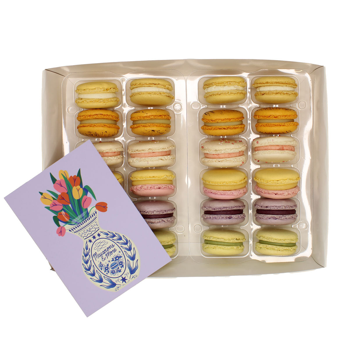 Box of assorted macarons with a decorative card on a white background