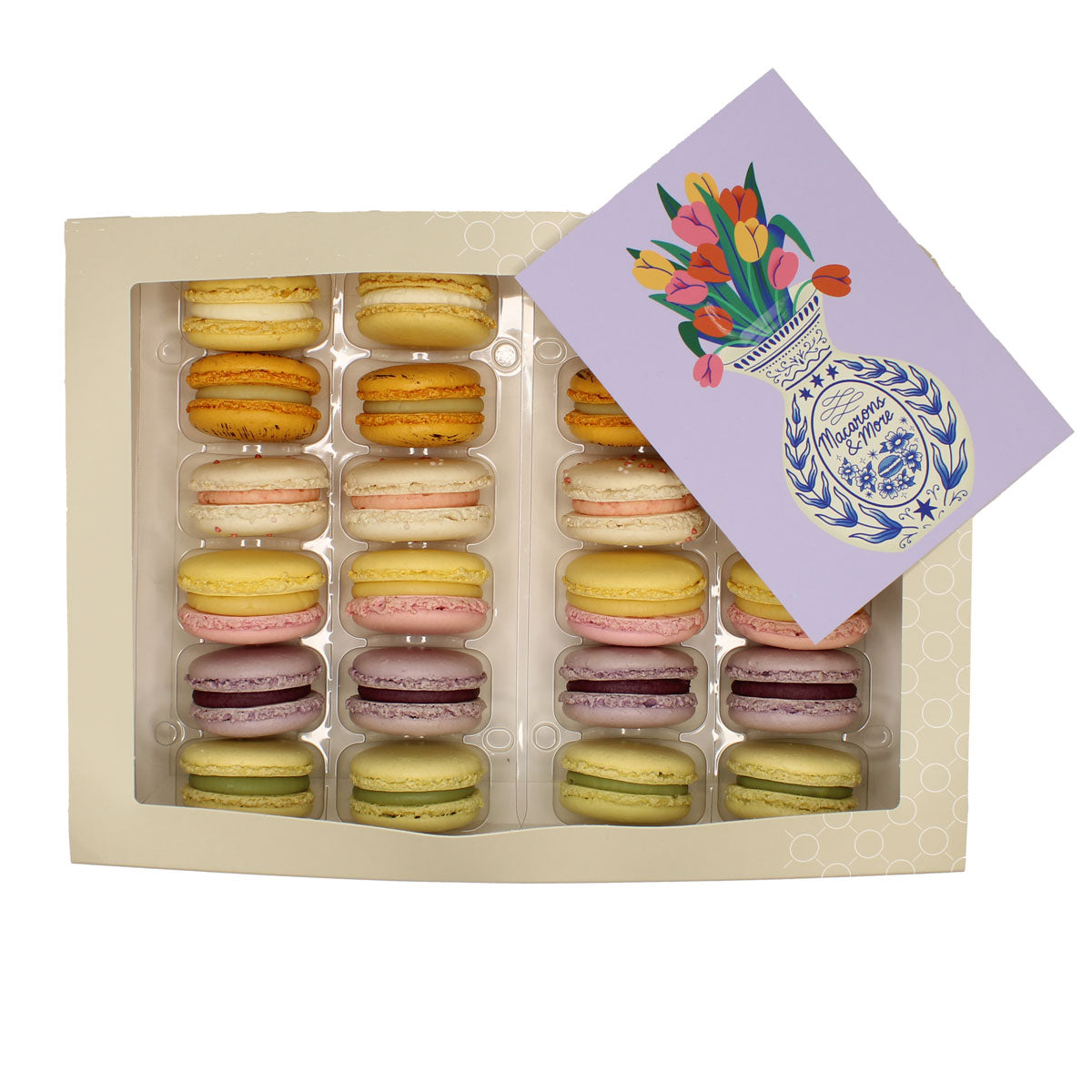 Box of colourful macarons with a decorative card on a white background