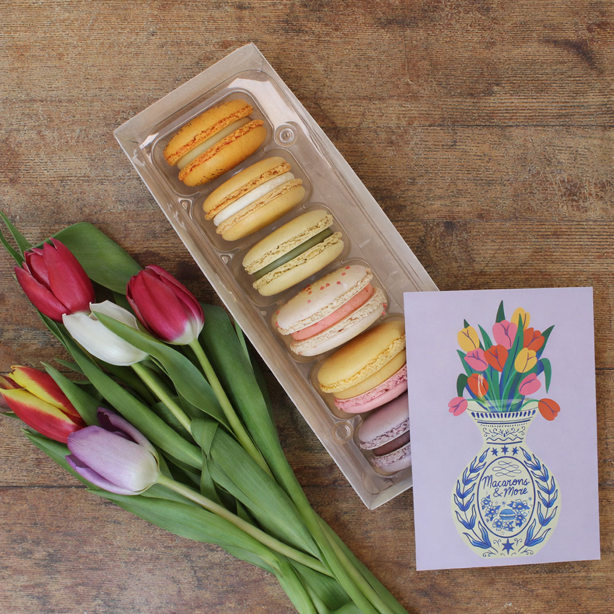 Box of macarons with tulips and a postcard with an illustration of tulips in a vase
