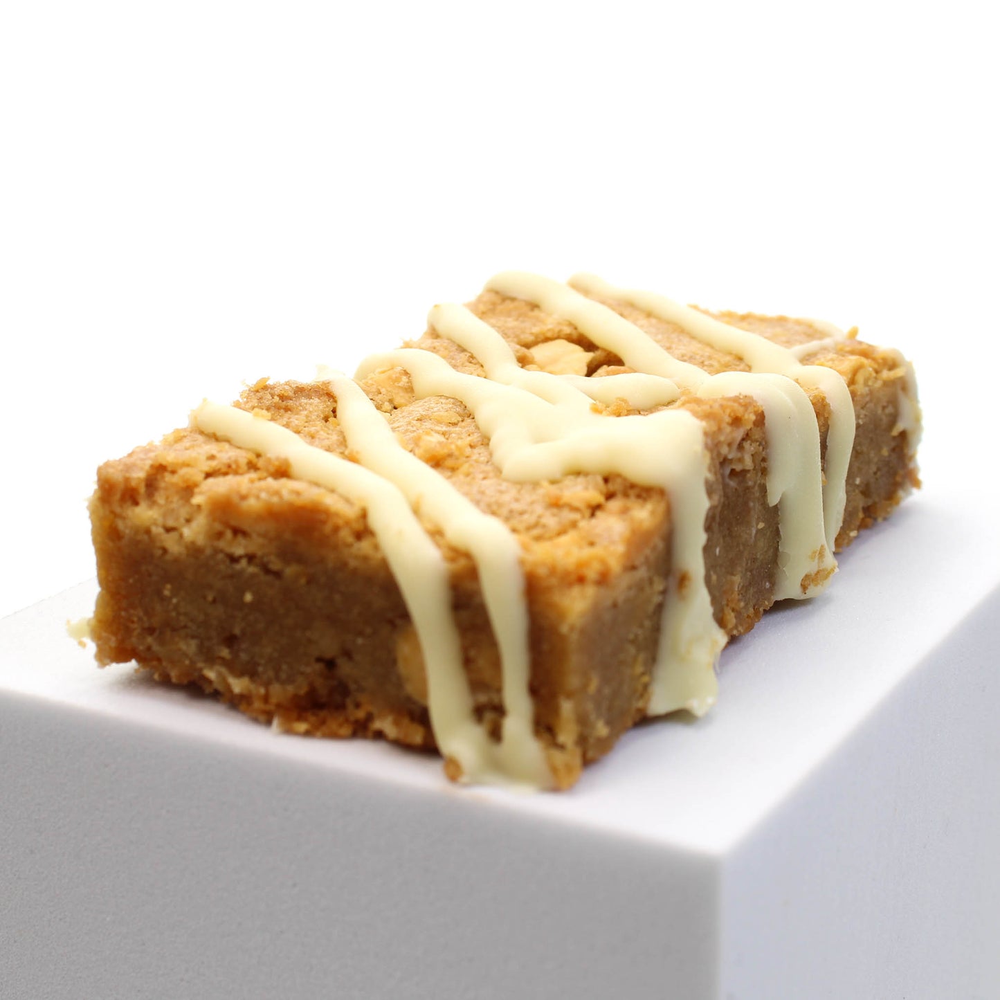 Peanut Butter Blondie showing off the drizzled white chocolate topping. Choose this homemade brownie for your chocolate gift box.