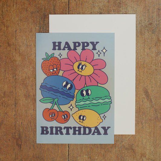 Blue card with colour illustrations of cartoon macarons, fruits and flowers with the text 'happy birthday'