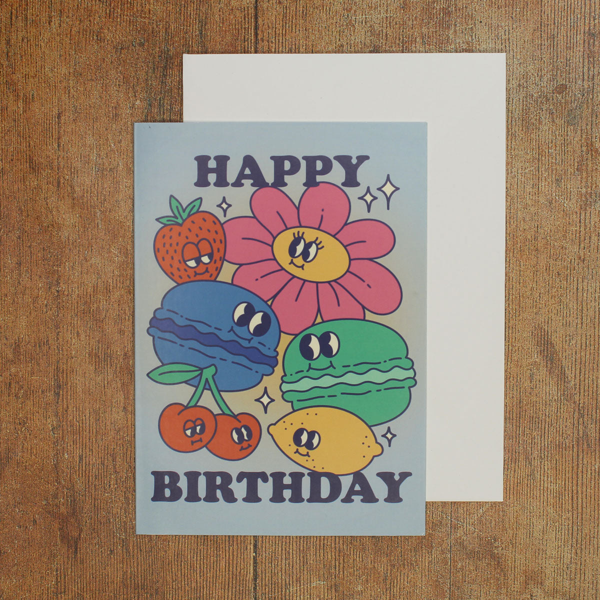 Blue card with colour illustrations of cartoon macarons, fruits and flowers with the text 'happy birthday'