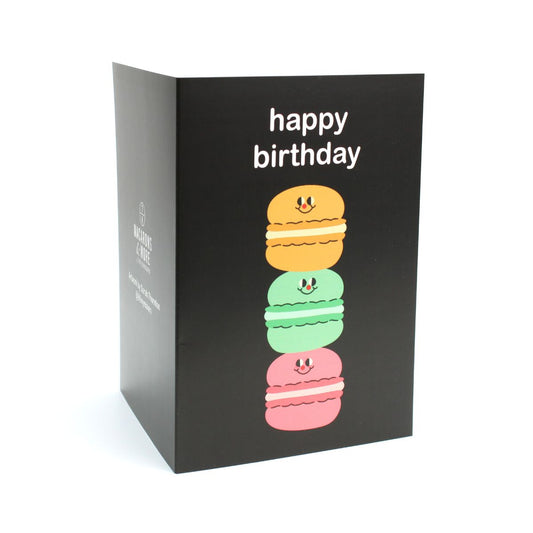 Black birthday card with colourful macaron illustration of three macarons stacked on top of one another and 'happy birthday' text