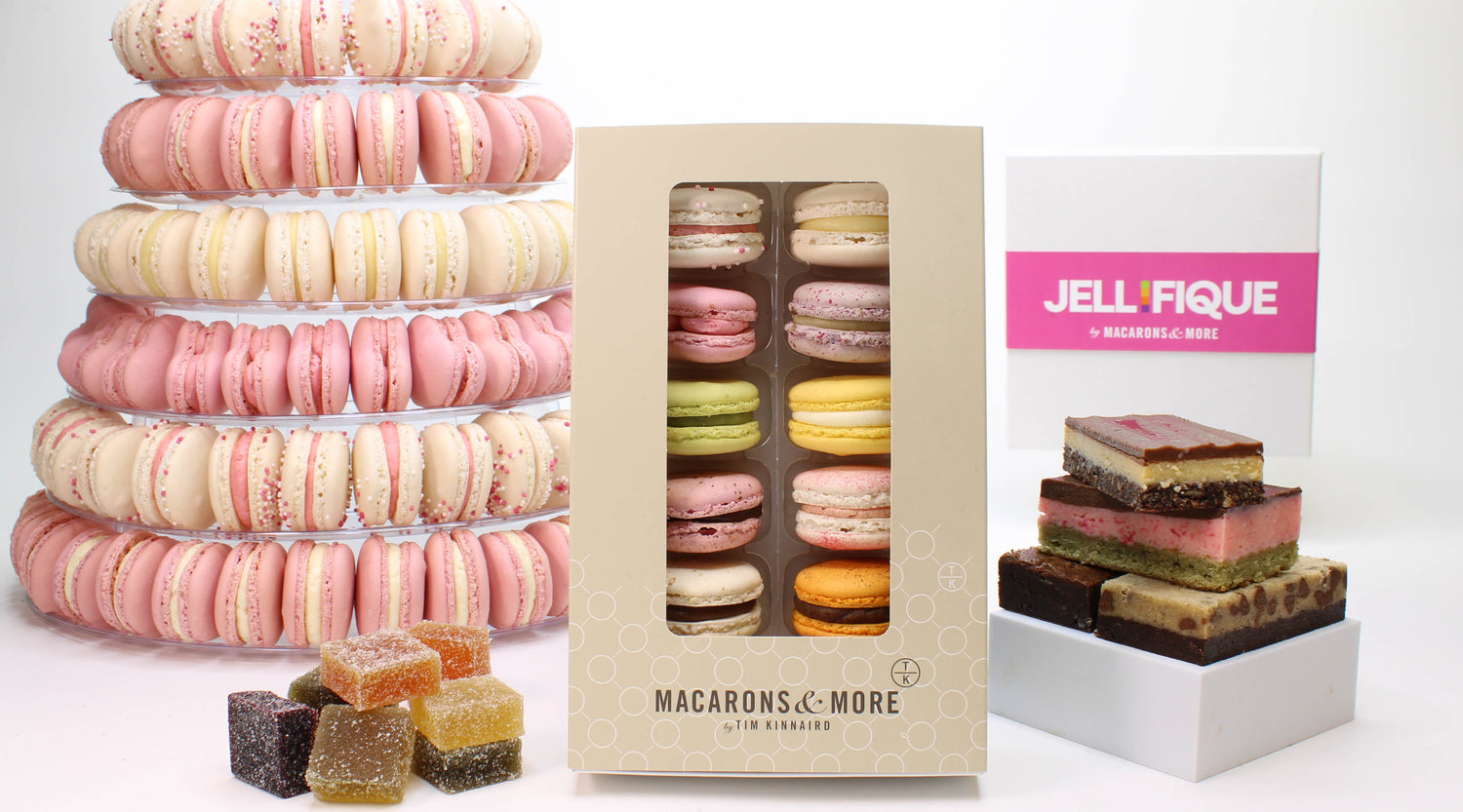 Selection of products. Pink and white macaron tower, brownies and bars, signature box of 12 macarons and pile of jellies.