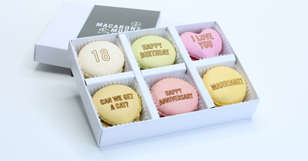 Box of personalised branded macarons in a white box with Macarons & More branding.