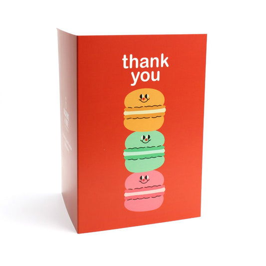 Orange greeting card with colorful illustration of a stack of macarons and 'thank you'