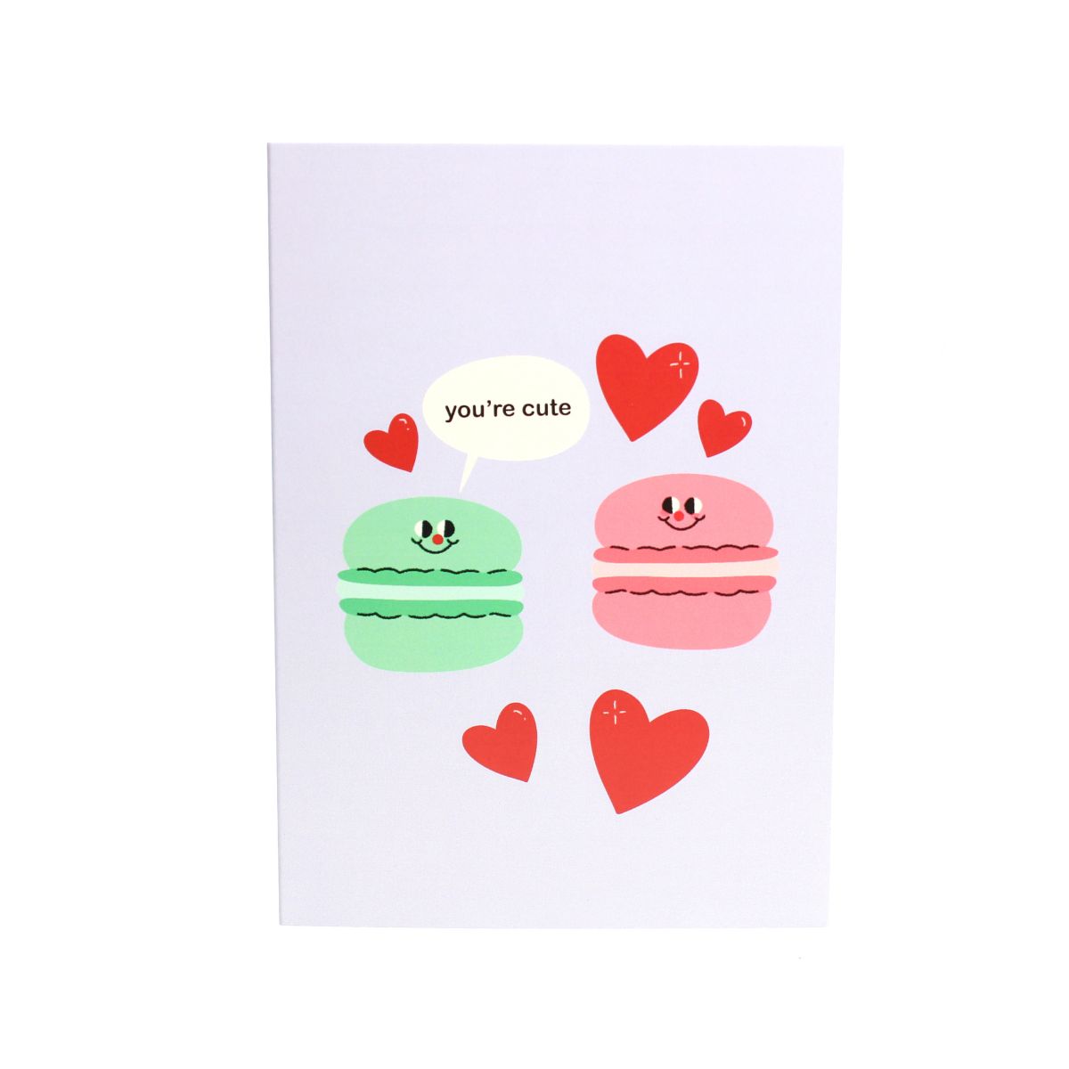 Card with cartoon macarons and hearts with a speech bubble reading 'you're cute'