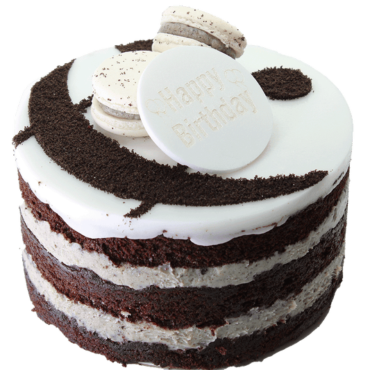 A Cookies & Cream cake with multiple layers, toped with icing, macarons, and ampersand design and a 'Happy Birthday' plaque.