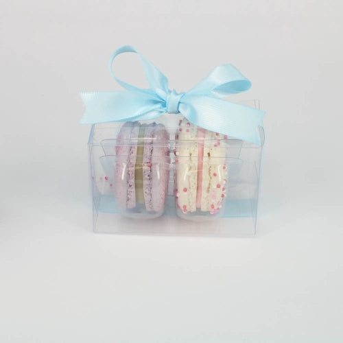 Two macarons in clear plastic box tied with blue ribbon.